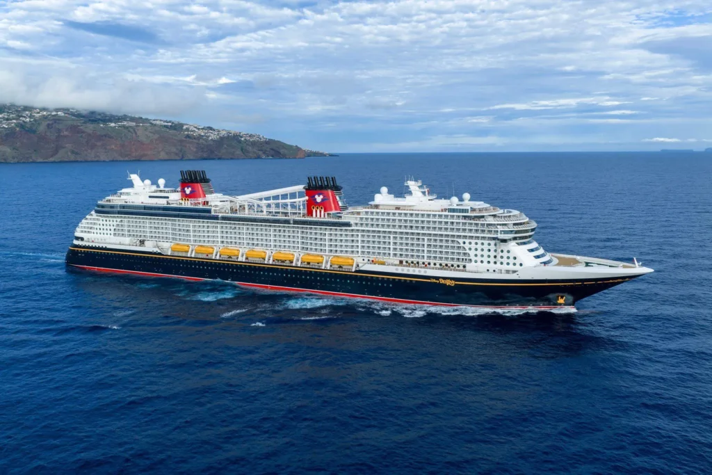 Le Disney Destiny navigue au large d'une île. Ce navire de classe Wish partage l'architecture et les caractéristiques qui inspireront le futur Disney Imagination au Japon.