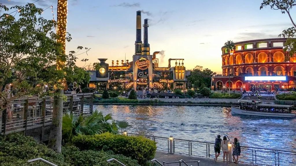 Vue de Universal CityWalk Orlando au coucher du soleil avec le restaurant Toothsome Chocolate Emporium au bord du lagon.